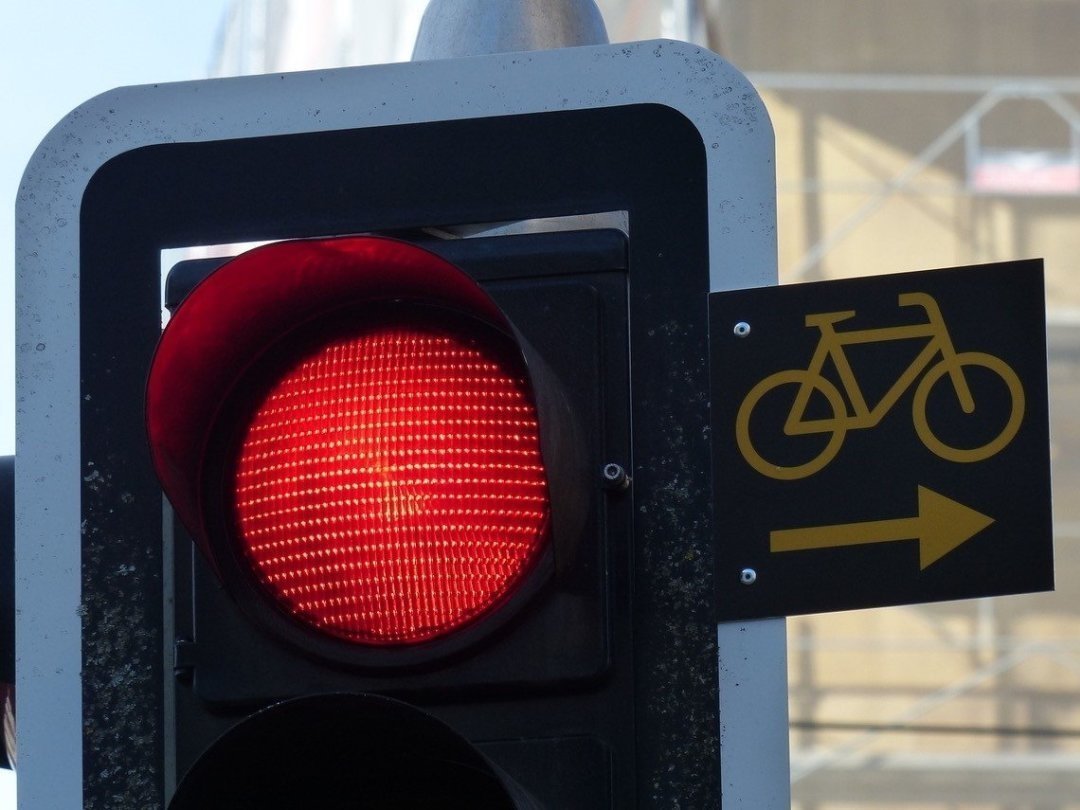 Une plaque signale aux cycliste et cyclomoteurs qu'ils peuvent tourner à droite quand le feu est rouge.