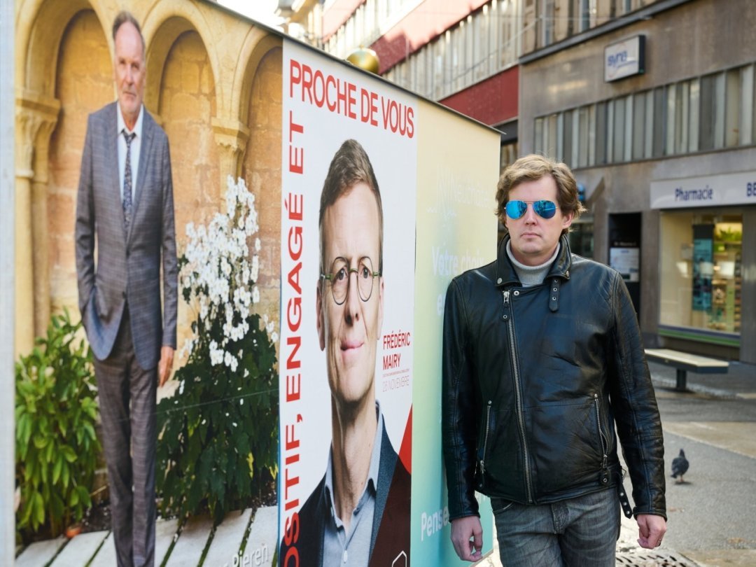 Thomas Wroblevski à côté des affiches des deux autres candidats à l'élection pour le Conseil d'Etat neuchâtelois du 26 novembre.